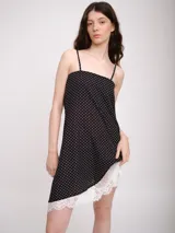 Vestido corto negro con lunares blancos, breteles finos y ruedo con encaje blanco.