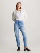 Pantalón de jean celeste con roturas en ambas piernas, de corte mom y tiro alto. Confeccionado con 79% algodón y 21% algodón reciclado.
