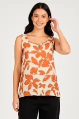 Musculosa de bretel ancho con estampado de flores color naranja sobre fondo crema, corte holgado y escote redondo con abertura en forma de gota.