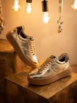 Zapatillas deportivas doradas de cuero con cordones color beige y suela marrón.