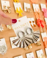 Aretes colgantes plateados, con forma de abanico plisado, sujetos a un aro circular.