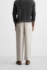 Pantalón de lino color marrón oscuro, de corte recto y relaxed fit. Tiene cintura elástica ajustable con cordón, bolsillos frontales y traseros de parche.