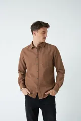Camisa marrón de manga larga con bolsillo en el pecho y cierre con botones.
