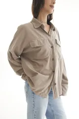 Camisa oversize color borgoña de pana con cuello camisero, cierre frontal con botones, dos bolsillos con solapa en el pecho y mangas largas con puños abotonados.