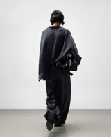 Pantalón ancho de pierna recta, color gris oscuro, confeccionado en acetato con textura arrugada y brillo satinado. Posee cintura elástica ajustable con cordón y bolsillos traseros.