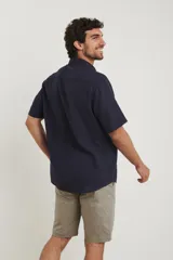 Camisa sport de manga corta color verde oliva, línea premium, con cuello clásico, cierre frontal con botones de coco y bolsillo de parche en el pecho. Confeccionada en lino y algodón.