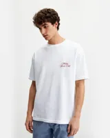 Remera blanca de algodón con cuello redondo y estampado en la espalda con la frase "Malibu Sports Club by Rona Studio" en color rojo.