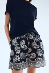 Short de tiro alto con estampado de motivos marinos en tonos azul y blanco. Presenta cintura elástica con cordón ajustable y bolsillos laterales.