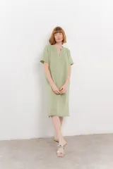 Vestido midi color verde claro, tejido en punto de algodón y poliéster, con escote en V, mangas cortas y aberturas laterales.