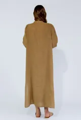 Vestido largo color beige de lino, con mangas largas abullonadas y volantes verticales en el frente. Cierre frontal con botones.