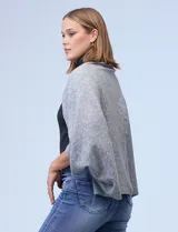 Cardigan negro de tejido suave, estilo poncho o capa, con cuello tipo chal y mangas amplias.