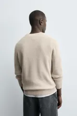 Sweater verde oscuro de punto, con cuello redondo y manga larga. Tejido en hilatura con mezcla de lana y acabados en rib.