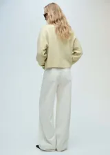 Sweater color crema con cuello en V, de tejido de punto y manga larga.