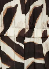 Mono largo de viscosa con estampado animal print en tonos marrones y beige. Tiene cuello camisero, cierre frontal con botones ocultos, cintura elastizada, bolsillos delanteros y diseño sin mangas.