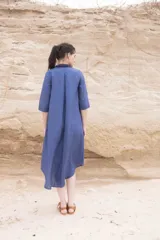 Vestido camisero azul de largo midi, con cuello mao con volados y mangas 3/4. Tiene cierre frontal con botones y un bolsillo de crochet aplicado.