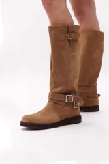 Bota de caña alta color negro, confeccionada en gamuza, con dos correas desmontables con hebillas metálicas.