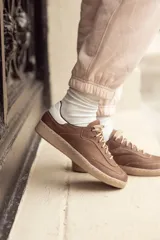 Zapatillas acordonadas de cuero color marrón chocolate, con detalle en blanco en el talón y suela color caramelo.