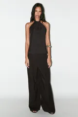 Top chaleco negro con cuello halter y cierre frontal con botones forrados.
