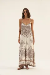 Mono largo de tirantes finos con estampado floral en tonos marrones sobre fondo blanco.