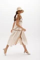 Vestido midi amarillo de lino, con volados en las mangas y detalle de volados y botones a lo largo del frente. Presenta un corte con talle marcado y falda escalonada.