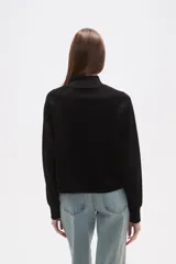 Buzo negro de manga larga con cuello tortuga y corte holgado.