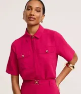 Camisa color beige de tela airflow, con cuello camisero, mangas cortas con detalle de pliegue, bolsillos con solapa en el pecho y cierre frontal con botones metalizados.