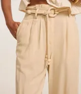 Pantalón pantalona color beige confeccionado en viscolino con viscosa certificada, con cintura con trabillas, cierre tradicional, cinturón de cuerda encapado con hebilla contrastante de adornos, esferas en las puntas y pliegues.
