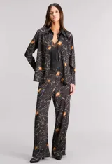Pantalón de pijama de satén texturado color negro con estampado de flores color naranja y blanco. Tiene calce relajado, cintura elastizada y bolsillos ocultos.