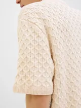 Polo de hombre color crema, tejido de punto cable, con cuello tipo polo, manga corta y cierre con botones.