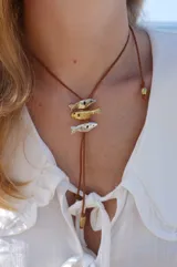 Gargantilla con hilo de algodón color camel y tres dijes de peces realizados en bronce, alpaca y plata 925.