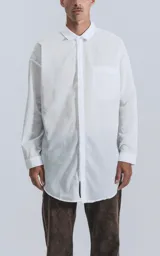 Camisa blanca de manga larga con bolsillo en el pecho, de calce oversize confeccionada en textil fresco y liviano.