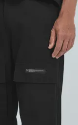 Pantalón cargo negro de corte recto con bolsillos laterales con solapa y etiqueta con texto en la pierna derecha.