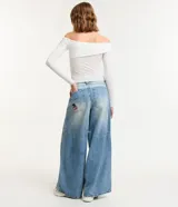 Blusa blanca texturizada con escote asimétrico hombro a hombro y mangas largas.