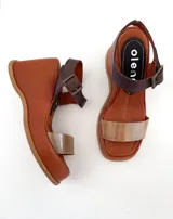 Sandalias de cuero color marrón con plataforma y tira delantera dorada. Tira trasera marrón con hebilla metálica.