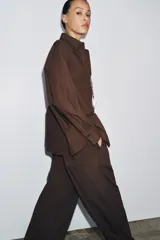 Camisa marrón de algodón con cuello solapa, manga larga con puños abotonados, bolsillo de parche en el pecho y cierre frontal con botones.