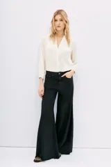 Pantalón de jean negro de corte oxford, tiro medio, con cintura y cadera ajustadas, y piernas anchas con recortes laterales.
