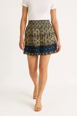 Falda mini con cintura elastizada, color beige con estampado de rombos azules y borde inferior con motivos geométricos.