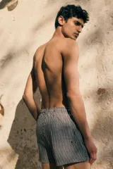 Short de baño negro con rayas verticales blancas, cintura elástica con cordón ajustable, bolsillos laterales y bolsillo trasero.