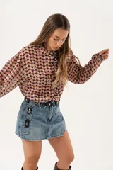 Minifalda de jean azul claro con corte evasé, detalle de short interno y cinturón negro con argollas metálicas.