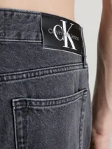 Pantalón de jean gris oscuro de corte recto, con tiro medio, cinco bolsillos y cierre con cremallera.
