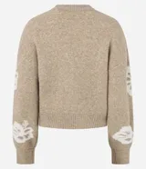 Cardigan cropped color beige con estampado de flores blancas, cuello redondo, cierre frontal con cremallera y mangas largas.