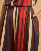 Pantalón de pinzas de talle alto con cintura elástica, bolsillos delanteros y pierna recta. Diseño a rayas verticales en tonos rojo, azul, beige y marrón.