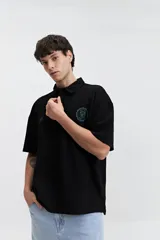 Polo azul marino con textura y corte oversize. Presenta un logo estampado en el pecho y mangas cortas.