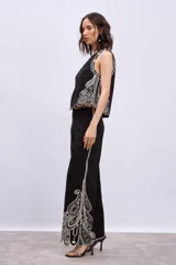 Pantalón blanco de corte ancho con bordados calados en forma de hojas en el ruedo.