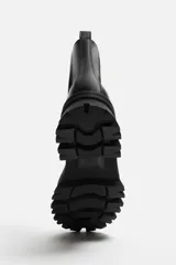 Bota Chelsea de cuero negro con elásticos laterales, tirador trasero y suela track de goma.