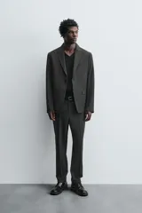Blazer regular fit color gris oscuro con diseño de cuadros, confeccionada en tejido con lana. Tiene cuello con solapas de muesca, manga larga con puños abotonados, bolsillo de vivo en el pecho, bolsillos de solapa en la cadera, bolsillo interior, aberturas en la espalda y cierre frontal con botones.
