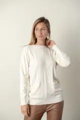 Sweater rojo de punto con cuello redondo y mangas largas. Presenta detalle de trenzado y distintos puntos en el frente, y dos bolsillos delanteros.