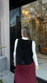 Chaleco negro de cuero descarne con terminación en picos y tachas metálicas.