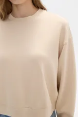 Buzo color beige de corte ancho y cuello redondo.