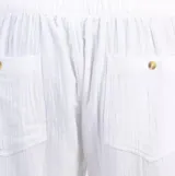 Pantalón de lino blanco, de corte recto y tiro medio, con cintura elástica ajustable con cordón y bolsillos laterales.